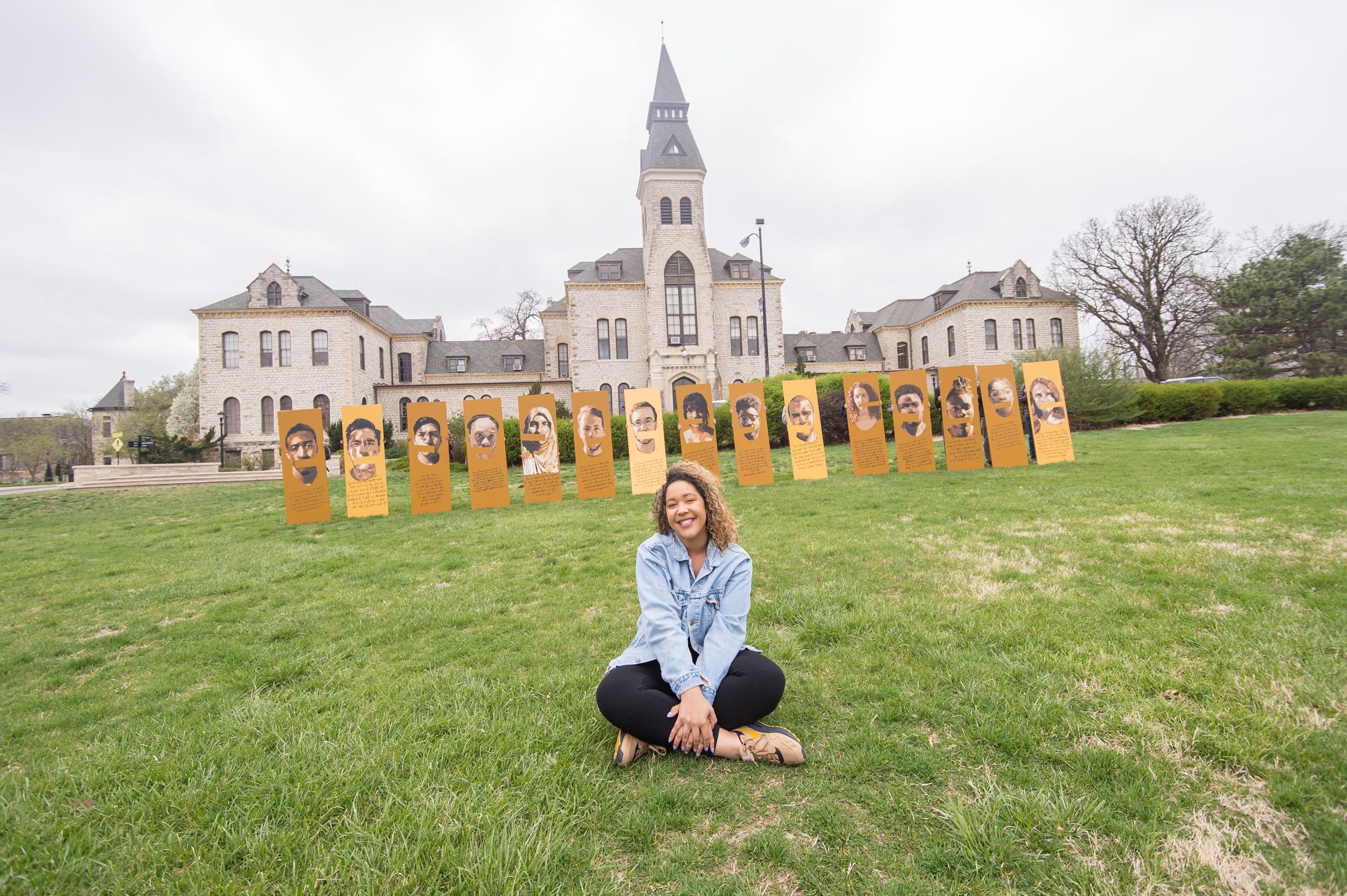 K-State master's student in architecture, Gabby Coleman, poses with the portraits she made of her fellow classmates