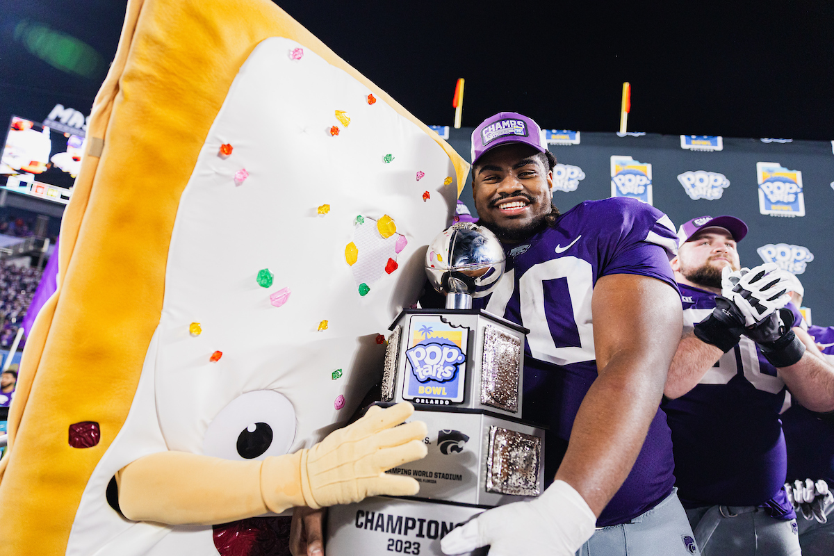 KT Leveston holds the Pop-Tarts Bowl 2023 Trophy with Strawberry the edible mascot next to him